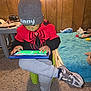 Vincent is registered to the contest to win money with this photo: child, tablet, beanie, red_hoodie, spiderman, gray_pants, sneakers, indoor, carpet, bed, toys, wood_paneling, furniture, person, technology, playing, kid, seat, focus, casual