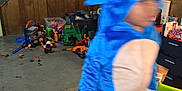 Vincent is registered to the contest to win money with this photo: child, blurry, blue_costume, toy, basement, carpet, wood_panel_wall, green_table, plastic_toy, clutter, indoor, playroom, motion_blur, person, costume, kid, floor, drawer, hat, fun