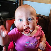 Phoenix joined the competition — help win amazing prizes! baby, child, blue_eyes, pink_clothing, high_chair, chocolate, smile, face, hand, indoor, wooden_furniture, table, kitchen, person, happy, cute, infant, expression, sitting, messy_face