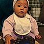 Nyla-Rose is registered to the contest to win money with this photo: baby, headband, controller, video_game, couch, slippers, pillow, blanket, child, indoors, curious, seated, clothing, hand, footwear, technology, gaming, expression, soft, cozy