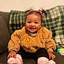 Nyla-Rose is registered to the contest to win money with this photo: baby, child, smiling, pigtails, pink_bows, brown_sweater, pink_socks, toy, couch, plaid_blanket, happy, indoor, portrait, infant, cute, sitting, cozy, face, hands, feet