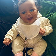 Nyla-Rose is registered to the contest to win money with this photo: baby, child, infant, smiling, happy, pigtails, pink_socks, bib, pacifier, clip, cozy_clothing, seated, couch, dark_background, indoor, cute, portrait, small_hands, expression, face