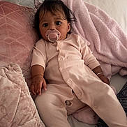 Nyla-Rose joined the competition — help win amazing prizes! baby, pacifier, pink_onesie, pillows, blanket, soft_texture, indoor, couch, relaxed, child, infant, sleepwear, cozy, comfort, hair, face, hand, footwear, person, home