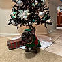 black_tree, carpet, celebration, christmas_ornaments, christmas_tree, cute, decorations, dog, festive, french_bulldog, gift_box, green_sweater, holiday, holiday_season, indoor, pet, smiling, teal_ornaments, tile_floor, white_ornaments