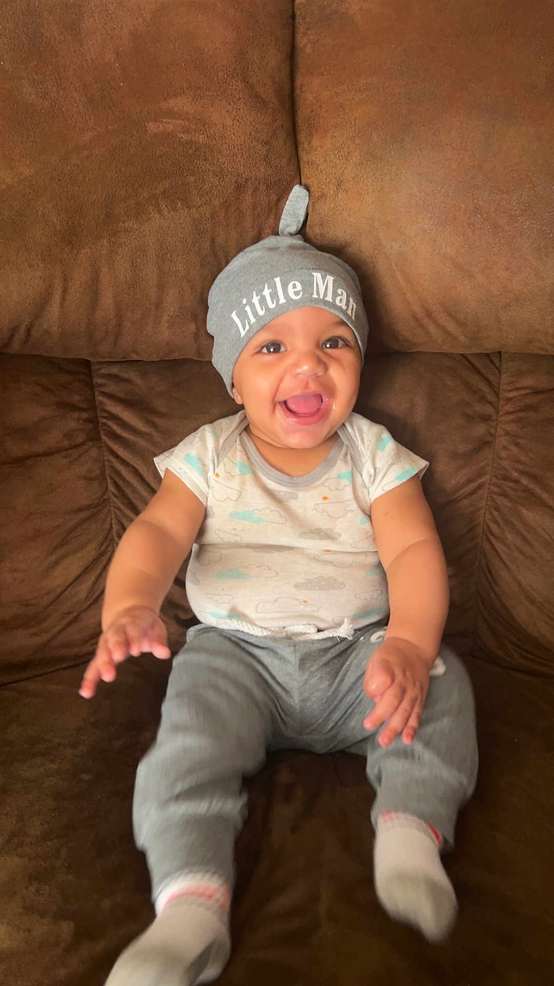 Elijah is registered to the contest to win money with this photo: baby, child, smile, happy, hat, clothing, pants, socks, couch, furniture, infant, person, cute, indoors, portrait, sitting, joyful, expression, skin, face
