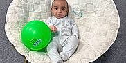 Elijah is registered to the contest to win money with this photo: baby, child, infant, plush_chair, green_ball, pajamas, carpet, indoor, office_chair, door, footwear, person, seated, toy, face, head, legs, hands, relaxed, casual