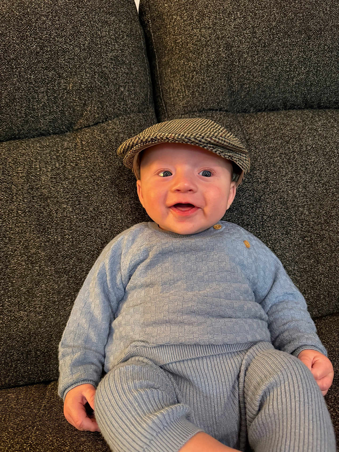 Roman joined the competition — help win amazing prizes! baby, child, smiling, cap, hat, blue_clothing, sitting, couch, indoor, knitwear, happy, portrait, cute, infant, human, one_person, face, headwear, casual, relaxed