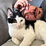 cat, man, sleeping, resting, beard, black_and_white_cat, couch, indoor, close_up, pet, companion, relaxation, hand, fur, face, animal, human, friendship, casual, comfort