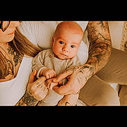 Sladjan a rejoint le concours — aidez-le/la à gagner de superbes lots ! baby, tattoos, hands, adult, woman, infant, portrait, closeup, warm_lighting, skin, couch, clothing, indoor, family, love, holding, person, casual, relaxed, gentle