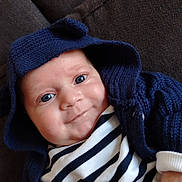 ézio a rejoint le concours — aidez-le/la à gagner de superbes lots ! baby, infant, smile, hoodie, knitted_clothing, blue_eyes, striped_shirt, couch, fabric, cozy, cute, portrait, child, young, indoor, apparel, person, closeup, happy, face