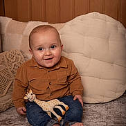 ézio a rejoint le concours — aidez-le/la à gagner de superbes lots ! baby, infant, smiling, blue_eyes, giraffe_toy, denim_jeans, corduroy_shirt, barefoot, cushion, throw_pillow, knitted_blanket, wood_paneling, indoor, portrait, sitting, soft_lighting, cozy, home_decor, cute, face