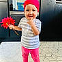 toddler, child, red_bandana, flower, pink_pants, striped_shirt, barefoot, indoor, kitchen, rug, oven, cabinet, smiling, playful, person, standing, hand, finger, cute, home