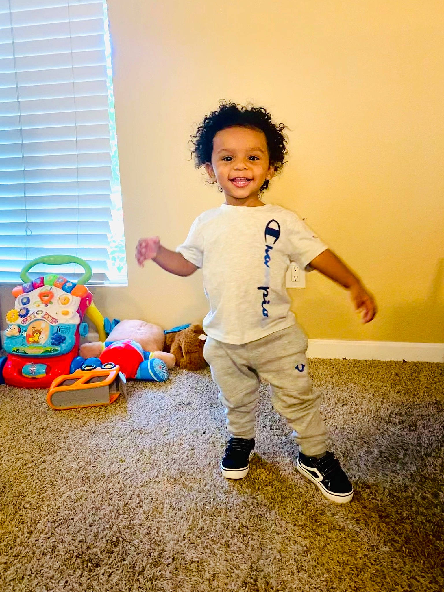Harlem is registered to the contest to win money with this photo: baby_toddler_clothing, child, flash_photography, flooring, fun, gesture, happy, joy, leisure, people_in_nature, person, playing_with_kids, room, shoe, sitting, sleeve, smile, sneakers, standing, toddler