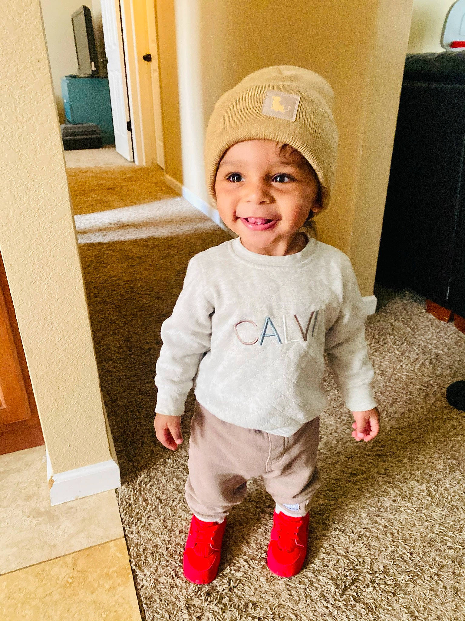 Harlem is registered to the contest to win money with this photo: baby, baby_toddler_clothing, cap, child, clothing, fashion_accessory, floor, flooring, fun, happy, headwear, helmet, joy, leg, mirror, person, skin, sleeve, smile, standing
