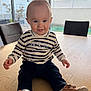 baby, child, indoor, table, wooden_table, striped_clothing, brown_shoes, smiling, sitting, curious, face, person, window, daylight, furniture, home, pants, shoe, cute, happy
