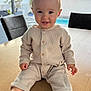Hugo participe au concours pour gagner de l'argent avec cette photo : baby, child, smile, table, indoor, pajamas, wooden_table, barefoot, face, happy, infant, cute, person, sitting, window, daylight, background, home, furniture, room