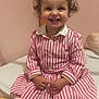 Ambre a rejoint le concours — aidez-le/la à gagner de superbes lots ! toddler, child, smiling, curly_hair, pink_dress, striped_clothing, white_tights, indoor, bed, wooden_frame, happy, person, portrait, cute, sitting, young_child, playful, room, cozy, baby