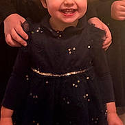 Ambre a rejoint le concours — aidez-le/la à gagner de superbes lots ! toddler, child, smiling, curly_hair, dress, sequins, hands, happy, portrait, indoors, person, young_child, cute, face, standing, fashion, clothing, joy, support, dark_background