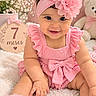 baby, infant, child, smiling, portrait, pink, flower_headband, ruffled_dress, bow, sitting, indoors, teddy_bear, flowers, milestone_sign, seven_months, nursery, blanket, soft_lighting, happy, photography