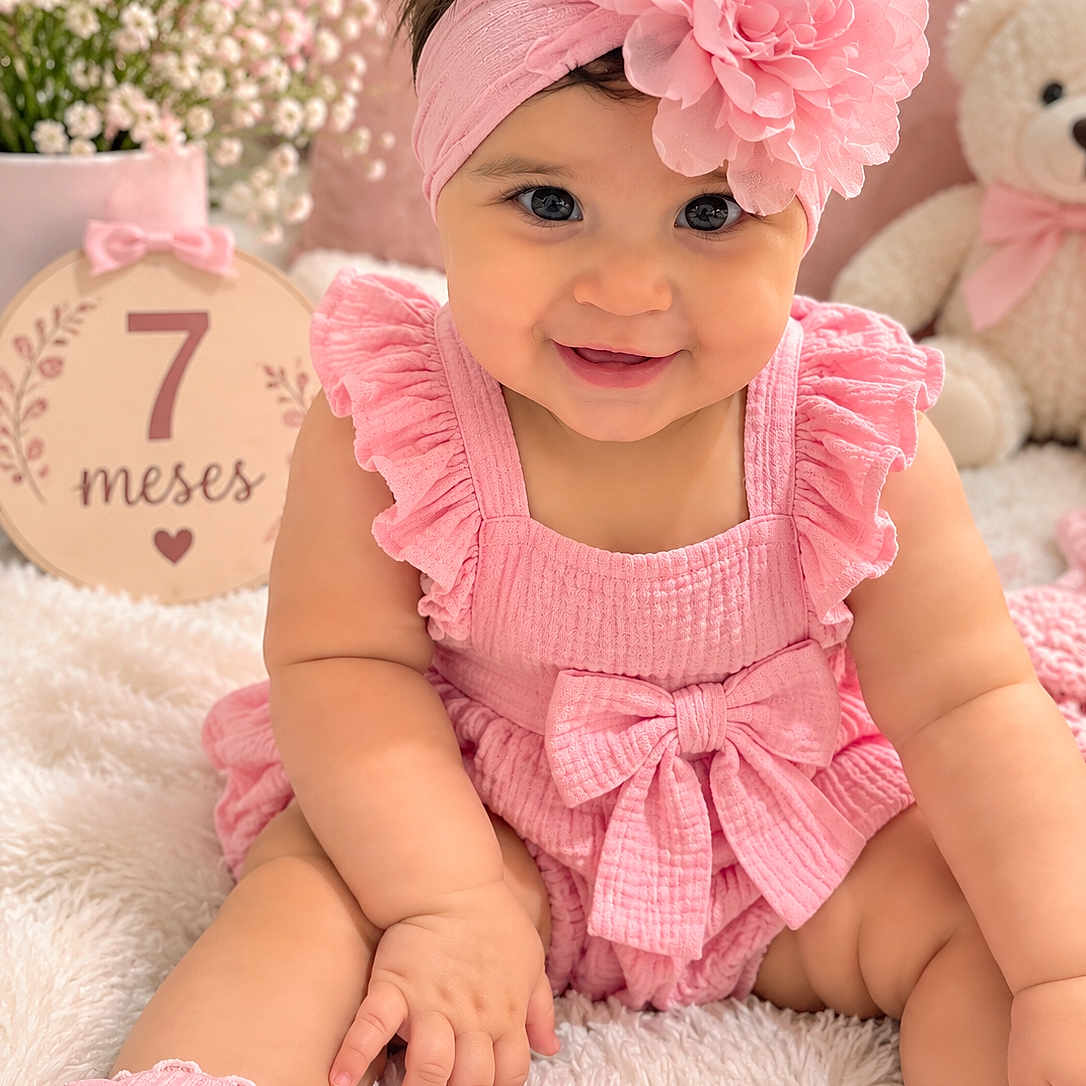Emely joined the competition — help win amazing prizes! baby, infant, child, smiling, portrait, pink, flower_headband, ruffled_dress, bow, sitting, indoors, teddy_bear, flowers, milestone_sign, seven_months, nursery, blanket, soft_lighting, happy, photography