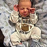 baby, newborn, sleeping, infant, blanket, clothing, socks, chain, football, pattern, cute, hands_up, soft, cozy, portrait, indoors, child, apparel, resting, peaceful