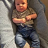 baby, infant, child, blanket, blue_blanket, clothing, striped_shirt, jeans, cuffed_pants, barefoot, hands, face, portrait, expression, indoor, soft_texture, cozy, cute, young, person