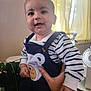 baby, child, smiling, striped_shirt, overalls, bear_patch, hand, indoor, curtains, fan, person, happy, cute, infant, portrait, clothing, face, holding, bright, window