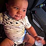 baby, child, infant, onesie, star_pattern, tissue, car_seat, can, seatbelt, hand, foot, face, expression, curious, indoor, vehicle, clothing, person, sitting, young