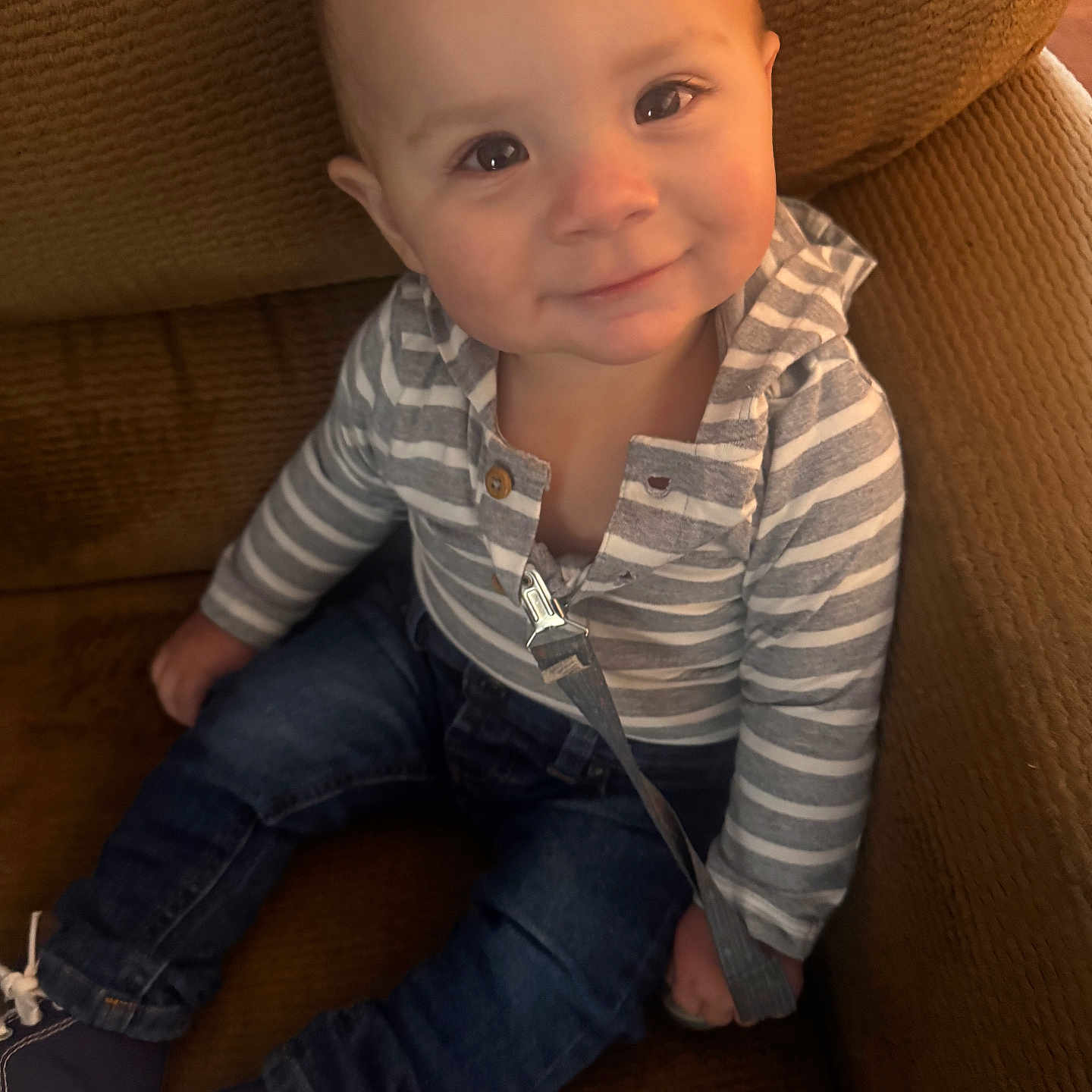 Kace is registered to the contest to win money with this photo: baby, brown_chair, candid, casual_clothing, child, cozy, cute, denim_jeans, face, happy, indoors, infant, person, portrait, seated, small_shoes, smiling, sneakers, striped_hoodie, young_child
