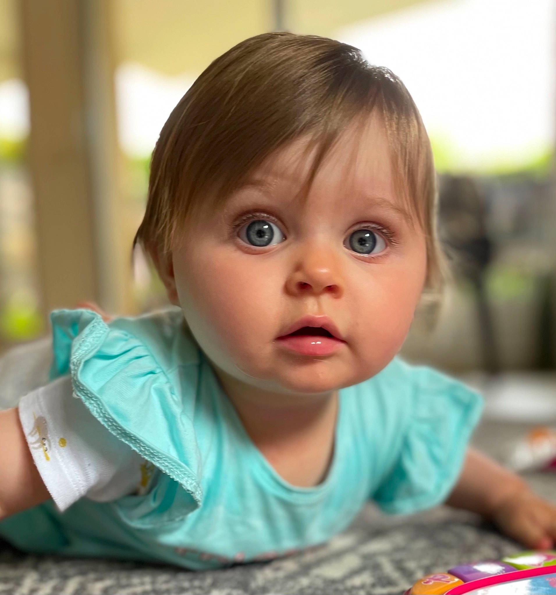 Lola a rejoint le concours — aidez-le/la à gagner de superbes lots ! baby, baby_toddler_clothing, blond, cheek, child, eyelash, finger, flooring, fun, happy, iris, leisure, nose, person, portrait_photography, room, sitting, skin, smile, surprise