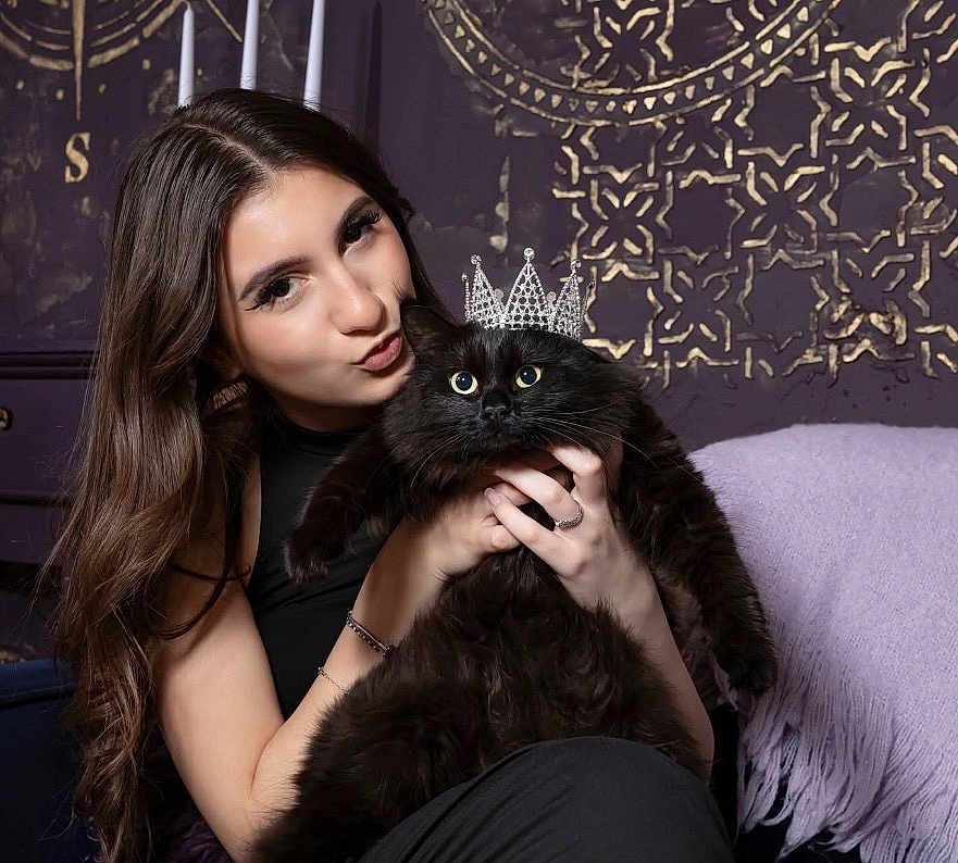 Blackie joined the competition — help win amazing prizes! woman, cat, black_cat, crown, portrait, indoor, long_hair, furry, pet, holding, jewelry, bracelet, ring, purple_blanket, decorative_wall, facial_expression, closeup, furniture, candid, cute