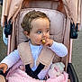 Lottie is registered to the contest to win money with this photo: toddler, stroller, baby, child, pink, blanket, snack, curly_hair, outdoor, seatbelt, clothing, pacifier, toy, comfort, candid, person, cute, baby_clothes, infant, seat