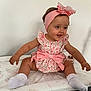 Lottie is registered to the contest to win money with this photo: baby, child, smiling, sitting, pink_bow, headband, floral_dress, white_socks, indoor, padded_surface, cute, happy, infant, portrait, young_child, soft_lighting, baby_girl, headwear, clothing, playful