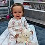 baby, child, pajamas, teddy_bear, changing_mat, smiling, indoor, toy, shelf, decor, carpet, furniture, cute, infant, playtime, soft_toy, room, happy, person, home