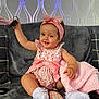 baby, child, girl, pink_bow, headband, floral_outfit, socks, blanket, toy_phone, keys, couch, gray_couch, smiling, happy, indoor, wallpaper, plush_blanket, cute, seated, home