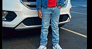 Yadiel Núñez is registered to the contest to win money with this photo: child, boy, smiling, denim_jacket, red_shirt, jeans, sneakers, car, white_car, parking_lot, outdoor, daytime, asphalt, buildings, residential, trees, casual_clothing, happy, person, portrait