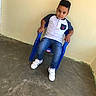 Yadiel Núñez joined the competition — help win amazing prizes! child, boy, plastic_chair, blue_chair, jeans, white_sneakers, casual_shirt, short_hair, indoor, concrete_floor, plain_wall, portrait, sitting, confident, young, casual_wear, floor, footwear, person, fashion