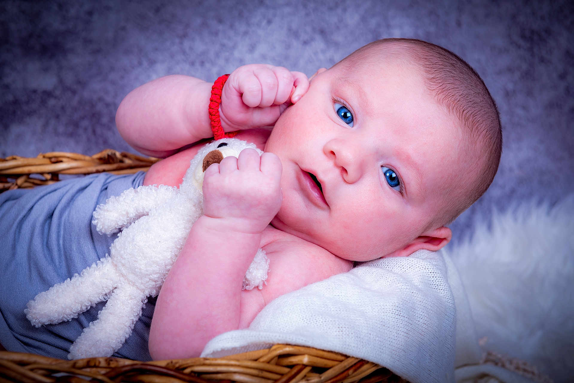 Matea a rejoint le concours — aidez-le/la à gagner de superbes lots ! baby, infant, blue_eyes, wicker_basket, stuffed_animal, plush_toy, red_bracelet, skin, closeup, portrait, soft_texture, blanket, cute, child, newborn, resting, indoors, cozy, expression, toddler