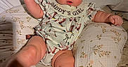 Averi is registered to the contest to win money with this photo: baby, child, infant, portrait, sitting, bed, bedding, floral, bow, green_bow, dress, clothing, face, eyes, smiling, fist, arms, legs, indoor, home