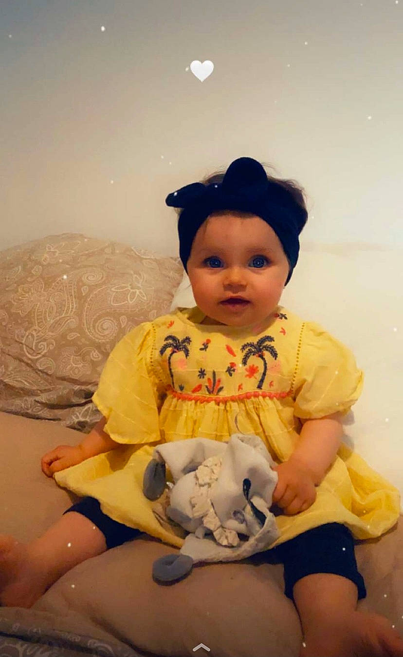 Louna participe au concours pour gagner de l'argent avec cette photo : abdomen, baby_toddler_clothing, black_hair, cheek, child, doll, eye, fun, happy, headwear, human_body, human_leg, mammal, person, sitting, skin, sleeve, thigh, toddler, toy