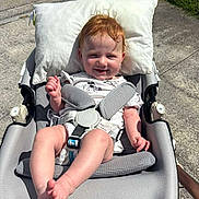 Taylor joined the competition — help win amazing prizes! baby, baby_rocker, child, clothing, concrete, cute, daylight, foot, grass, hand, happy, infant, outdoor, person, pillow, red_hair, relaxing, seat_belt, smiling, sunlight