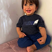 Milan is registered to the contest to win money with this photo: barefoot, casual, child, closeup, cross_legged, cute, happy, indoor, navy_blue_clothing, person, playful, plush_cushion, portrait, short_hair, sitting, smiling, soft_lighting, toddler, wall, young_child