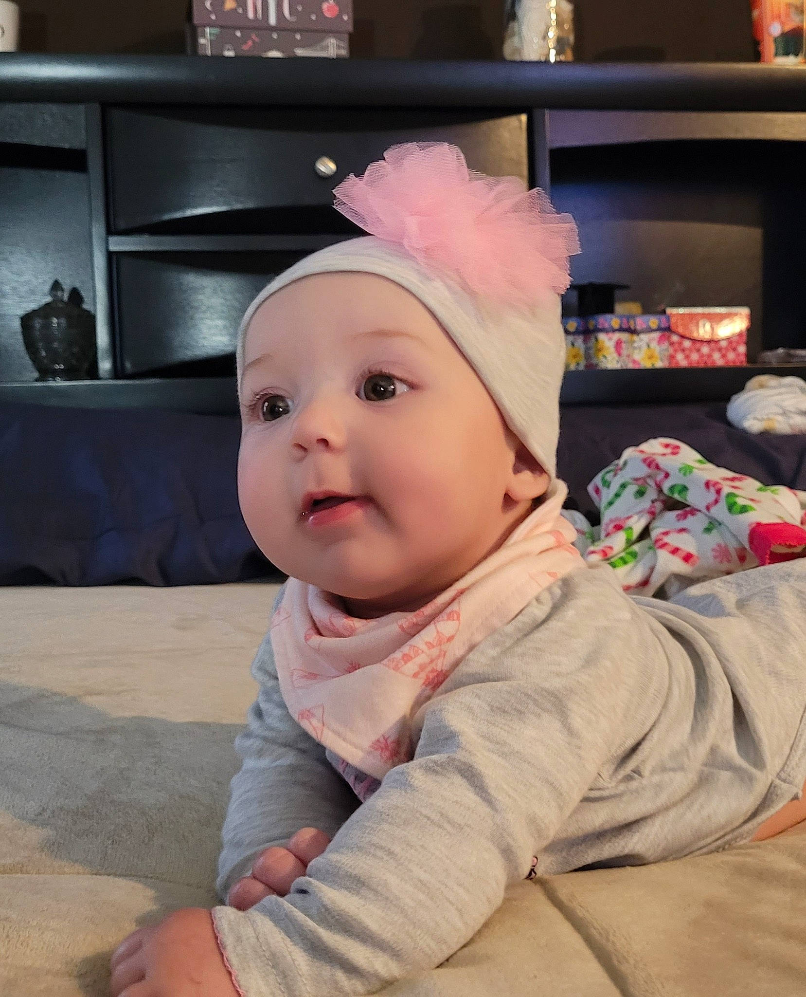 Oaklee is registered to the contest to win money with this photo: baby, baby_toddler_clothing, beanie, cap, cheek, child, comfort, costume_hat, fashion_accessory, flooring, happy, headwear, home_appliance, person, portrait_photography, room, shelf, sitting, sleeve, television