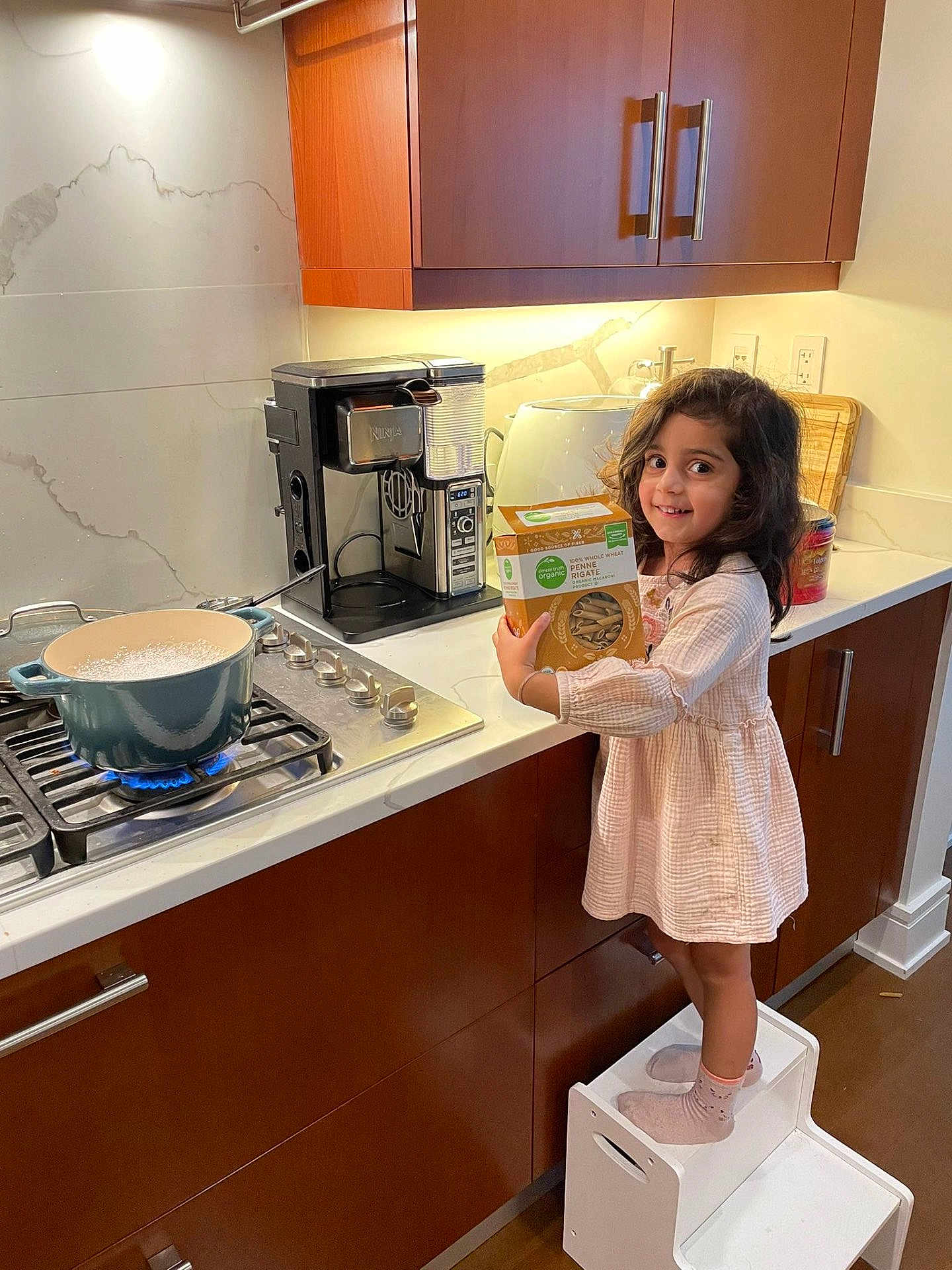 Aadya joined the competition — help win amazing prizes! child, girl, kitchen, stove, pot, pasta_box, step_stool, socks, dress, smile, cooking, countertop, cabinet, appliance, modern, indoor, happy, food, young_child, curly_hair