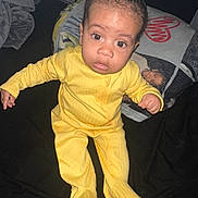 Kyrie is registered to the contest to win money with this photo: baby, blanket, child, cozy, cute, expression, face, human, indoors, infant, looking_up, person, portrait, sitting, sleepwear, small_hands, soft_texture, wide_eyes, yellow_onesie, young_child