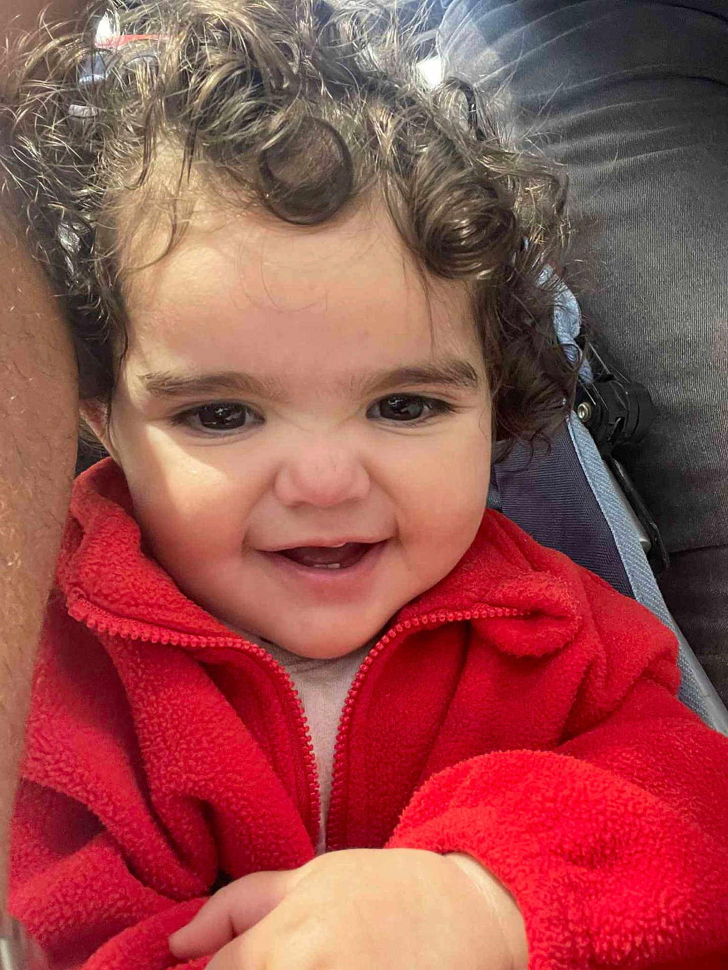 Rahma participe au concours pour gagner de l'argent avec cette photo : toddler, child, curly_hair, red_jacket, smiling, happy, face, portrait, baby, cute, cozy, warm_clothing, hands, indoor, person, closeup, expression, joyful, infant, baby_face