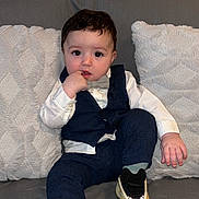 Aymen a rejoint le concours — aidez-le/la à gagner de superbes lots ! bow_tie, casual, child, clothing, couch, cushions, expression, face, fashion, footwear, hair, hand, indoor, pants, person, seated, sneakers, socks, toddler, vest