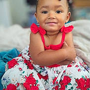 Serenity is registered to the contest to win money with this photo: arms_crossed, beads, braids, child, colorful, cute, dress, face, fashion, floral_pattern, happy, indoors, person, portrait, red_roses, sitting, skin, smile, toddler, young_child
