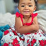 arms_crossed, beads, braids, child, colorful, cute, dress, face, fashion, floral_pattern, happy, indoors, person, portrait, red_roses, sitting, skin, smile, toddler, young_child