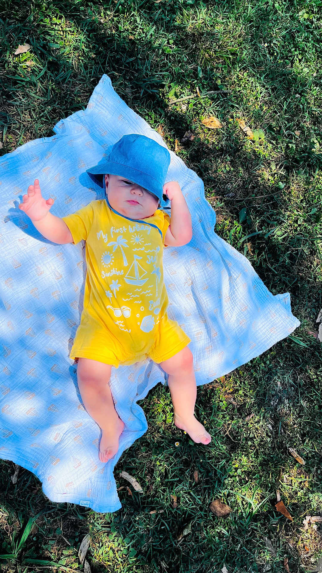 David a rejoint le concours — aidez-le/la à gagner de superbes lots ! baby, blanket, blue_hat, casual_clothing, child, feet, grass, greenery, infant, lying_down, nature, one_person, outdoor, person, relaxing, skin, summer, sunlight, sunny, yellow_clothing